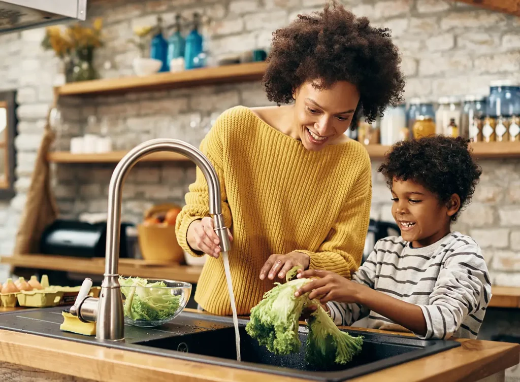 mother and son washing vegetables with their properly working faucet